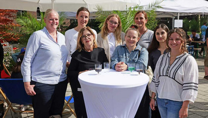 Mehrere Mitarbeiterinnen stehen um einen weißen Stehtisch und blicken fröhlich in die Kamera beim Albertinen-Sommerfest für die Mitarbeitenden aus den unterschiedlichen Einrichtungen der Immanuel Albertinen Diakonie am Standort Schnelsen auf dem Platz vor der Kirche am Albertinen Krankenhaus. Mehrere Mitarbeiterinnen stehen um einen weißen Stehtisch und blicken fröhlich in die Kamera beim Albertinen-Sommerfest für die Mitarbeitenden aus den unterschiedlichen Einrichtungen der Immanuel Albertinen Diakonie am Standort Schnelsen auf dem Platz vor der Kirche am Albertinen Krankenhaus.