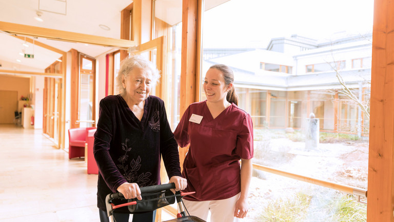 Seniorin geht mit Pflegerin im Hospiz spazieren