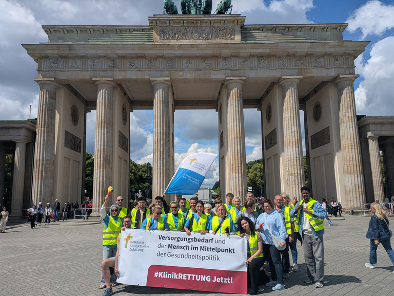 Mitarbeitende mit Banner vor Brandenburger Tor