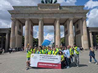 Mitarbeitende mit Banner vor Brandenburger Tor