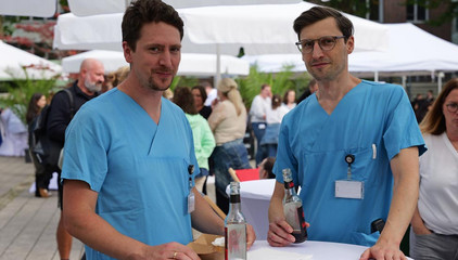Zwei Ärzte in blauer Funktionsgleidung an einem Stehtisch beim Albertinen-Sommerfest für die Mitarbeitenden aus den unterschiedlichen Einrichtungen der Immanuel Albertinen Diakonie am Standort Schnelsen auf dem Platz vor der Kirche am Albertinen Krankenhaus. Zwei Ärzte in blauer Funktionsgleidung an einem Stehtisch beim Albertinen-Sommerfest für die Mitarbeitenden aus den unterschiedlichen Einrichtungen der Immanuel Albertinen Diakonie am Standort Schnelsen auf dem Platz vor der Kirche am Albertinen Krankenhaus.