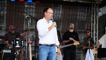 Andreas Schneider, Geschäftsführer im Ev. Amalie Sieveking Krankenhaus, steht auf der Konzertbühne mit einem Mikrofon bei seiner Rede beim Sommerfest 2026 auf dem Gesundheitscampus Volksdorf des Evangelischen Amalie Sieveking Krankenhauses, der Residenz am Wiesenkamp, des Feierabendhauses Volksdorf und der Albertinen Kindertagesstätte Volksdorf. Andreas Schneider, Geschäftsführer im Ev. Amalie Sieveking Krankenhaus, steht auf der Konzertbühne mit einem Mikrofon bei seiner Rede beim Sommerfest 2026 auf dem Gesundheitscampus Volksdorf des Evangelischen Amalie Sieveking Krankenhauses, der Residenz am Wiesenkamp, des Feierabendhauses Volksdorf und der Albertinen Kindertagesstätte Volksdorf.