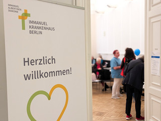 Banner mit Schriftzug Herzlich Willkommen am Eingang in den Saal